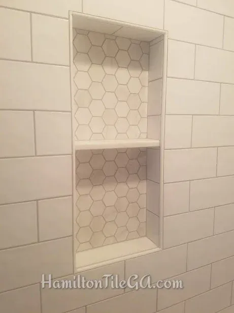 A custom 12”x28” inset box with custom hard surface shelves. Edged with Kerdi profiles.
